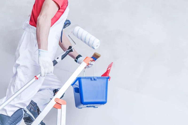 professional paintier climbing up portable stairs to start painting on wall